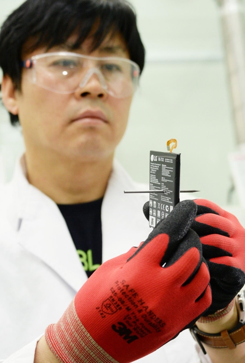 ▲ LG전자 연구원이 날카로운 못으로 관통하는 '관통 시험' 후 이상이 없는 LG G6 배터리를 들어보이고 있다. [LG전자 제공]