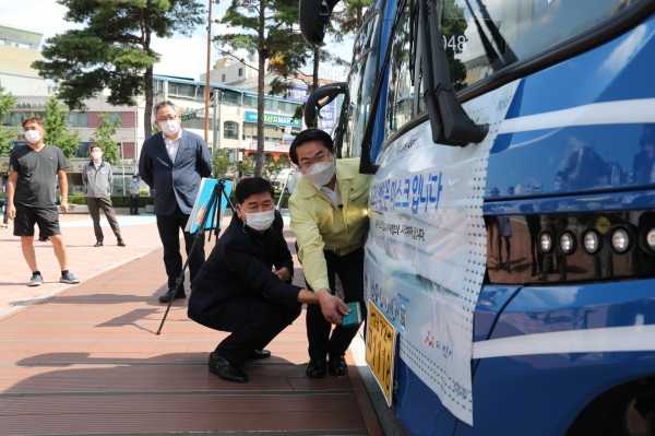 오세현 아산시장과 장훈종 선문대교수(왼쪽)가 시내버스에 ‘최고의 백신은 마스크입니다’ 홍보문구를 붙이고 있다. 아산시 제공