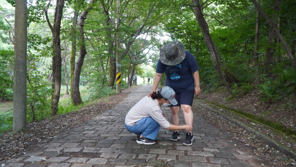 지난 5일 대전 서구 도솔산을 오르던 중 발달장애인 이지영(19‧왼쪽) 양의 신발끈이 풀리자 어머니 성경미(46) 씨가 묶어주고 있다. 사진=김성준 기자