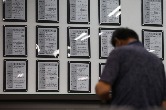 한 시민이 구인 게시판 앞에 앉아 있다. 사진=연합뉴스.
