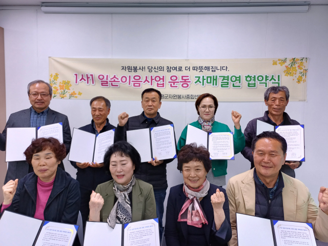김남순 센터장(앞줄 오른쪽 두 번째)과 자매결연을 한 5개 단체와 마을 대표들이 협약서를 들고 파이팅을 외치고 있다. 증평군 제공