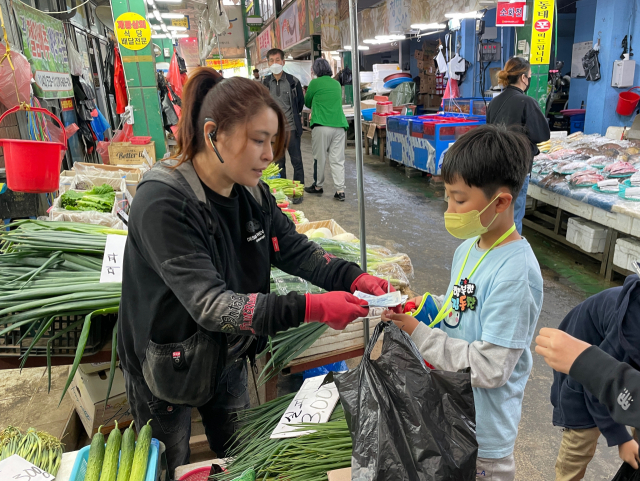 26일 대전도마큰시장을 찾은 대전산서초등학교 학생이 직접 물건을 구매하고 온누리상품권으로 결제하고 있다. 사진=한유영 기자