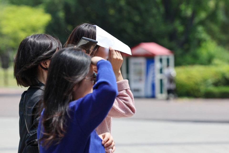 한 시민이 종이로 햇빛을 가리며 이동하고 있다. 사진=연합뉴스.