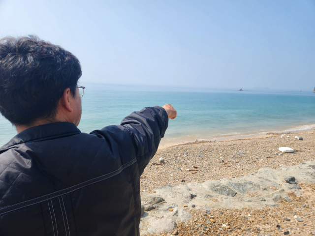 충남 보령 장고도에서 한 유류피해민이 2007년 충남 태안 기름유출 사고 당시 기름이 흘러들어왔던 바다를 가리키고 있다. 사진=김지현 기자
