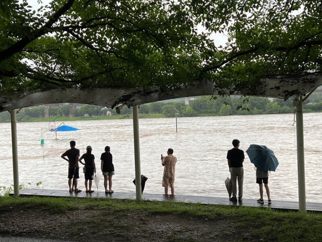 14일 대전에 내린 폭우로 인해 갑천변의 수위가 높아진 가운데 전민동 천변에서 시민들이 이 모습을 걱정스럽게 바라보고 있다. 사진=김윤주 기자