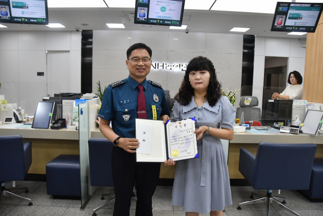 길재식(왼쪽) 중부경찰서장이 23일 보이스피싱 피해를 예방한 은행직원에게 감사장을 주고 기념촬영하고 있다. 대전중부서 제공