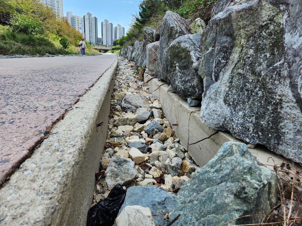 반석천변 산책로와 제방 사이에 쌓아둔 돌들이 유실돼 깊게 파인 모습. 사진=김성준 기자