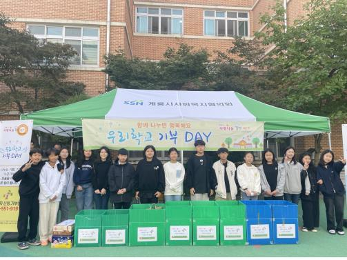 ▲계룡시두마초등학교는 지난 12일 아침 등교 시간에 계룡시사랑나눔푸드뱅크, 전교생, 교직원이 함께 참여하는 ‘우리학교 기부 Day’ 행사를 가졌다.