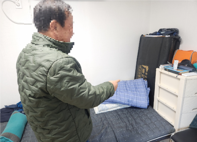 오응찬 씨가 임시조립주택에서 방한 용품을 가리키고 있다. 사진=김지현 기자
