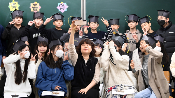 15일 대전 서구 둔산초등학교에서 열린 졸업식에서 졸업생들이 종이로 제작한 학사모를 쓰고 담임교사와 기념촬영을 하고 있다.이경찬 기자 chan8536@cctoday.co.kr