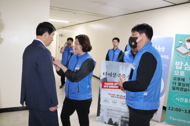 충주시공무원노조는 23일 악성민원으로 숨진 김포 공무원 49제를 추모하며 악성민원 근절 캠페인을 가지며 출근하는 조길형 시장에게 검은 리본을 달아주고 있다.사진=충주시
