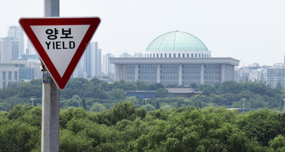 여야가 22대 국회 상임위원회를 배분하는 원구성 문제를 두고 강대강 대치를 이어가고 있는 지난 9일 서울 마포구 서강대교에 설치된 교통표지판 너머로 국회의사당이 보인다. 2024.6.9 사진=연합뉴스.