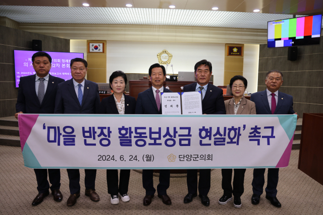 마을 반장 활동보상금 현실화 촉구 건의문 현수막을 들고 있는 조성룡 군의장을 비롯한 의원 일동. 단양군의회 제공