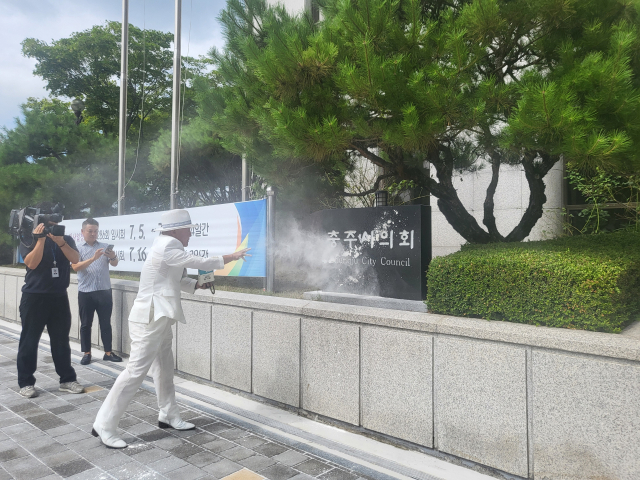 오천도 애국국민운동대연합 대표가 16일 오전 충주시의회 한 의원에 불미스런운을 비판하면서 시의회 표지석에 밀가루 세례를 퍼붓고 있는 모습이다.사진=김의상 기자