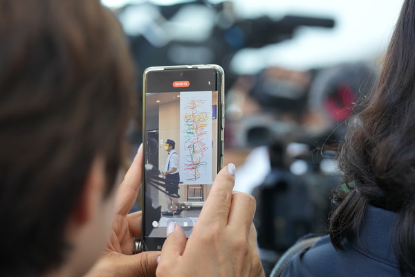 ​​​​​​​14일 DCC 제2전시관에서 열린 2024 K-아트페어대전 VIP 개막식 오프닝 공연에서 한 관객이 이상돈 작가의 드로잉쇼를 촬영하고 있다.