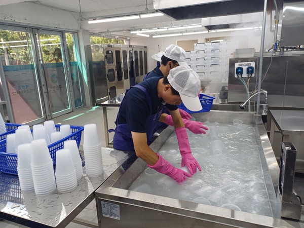 ▲ 충남지역자활센터의 푸른약속 사업단 관계자가 다회용기 세척을 하고 있다. 예산군사회복지협의회 제공