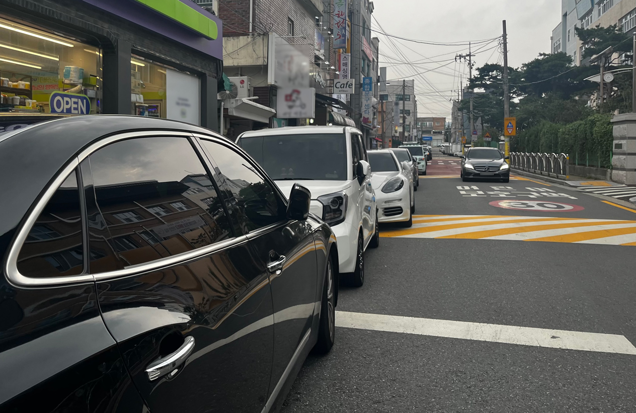 22일 대전 서구의 한 초등학교 후문 통학로에 위치한 상가들로 불법주정차 차량이 즐비해있다. 사진=조정민 기자