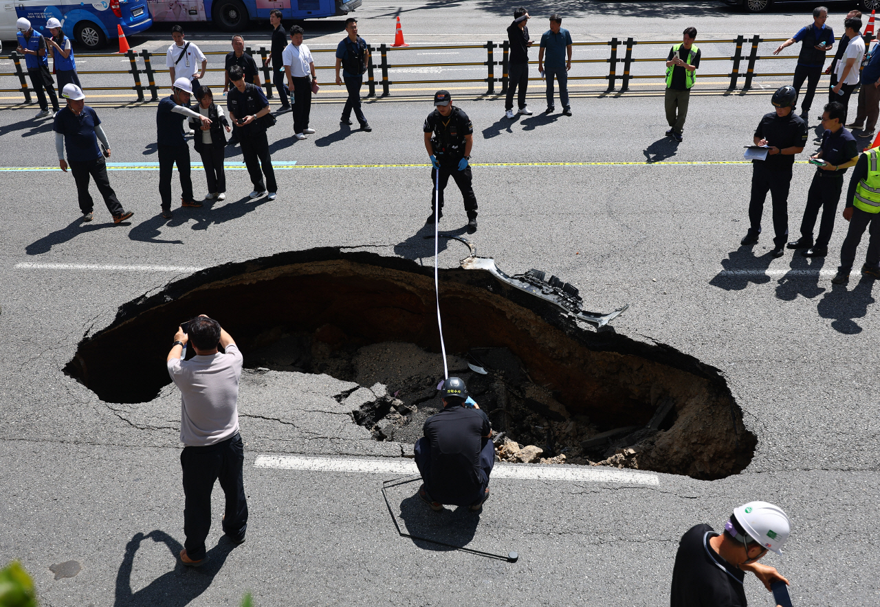 29일 오전 서울 서대문구 연희동 성산로에서 발생한 땅 꺼짐(싱크홀) 현상 현장에서 과학수사대가 사고 폭을 측정하고 있다.이 사고로 승용차 탑승자 2명이 병원으로 후송됐다. 2024.8.29 사진=연합뉴스. 
