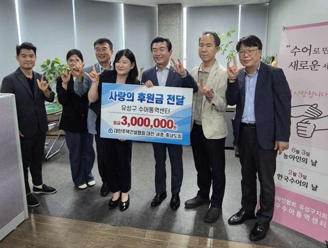 김용관 대한주택건설협회 대전·세종·충남도회 회장과 임직원들이 5일 대전시 유성구 수어통역센터에서 박옥경 대전농아인협회 유성구지회 지회장 겸 센터장과 성금 전달식을 가진 뒤 기념촬영을 하고 있다.협회 제공