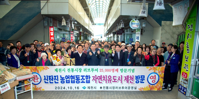 대전 신탄진농협 성정희 조합원이 제천시 전통시장 러브투어 2만5000번쨰 방문객으로 선정돼 김창규 제천시장이 꽃다발과 지역특산품을 전달, 축하하고 민권기 조합장 등과 기념 촬영을 가졌다. 제천시 제공