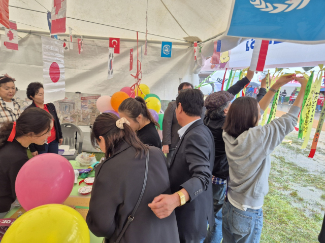 ▲홍보부스를 찾은 관람객들이 ‘우리의 소원은 통일’이라고 적힌 통일기원 리본을 달고 있다.