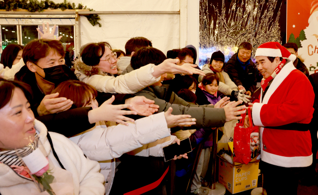 김동일 보령시장(사진 오른쪽)이 지난해 대천 겨울바다 사랑축제에서 산타복을 입고 행사에 참여한 관광객 등에게 선물을 나눠주고 있다. 보령시 제공