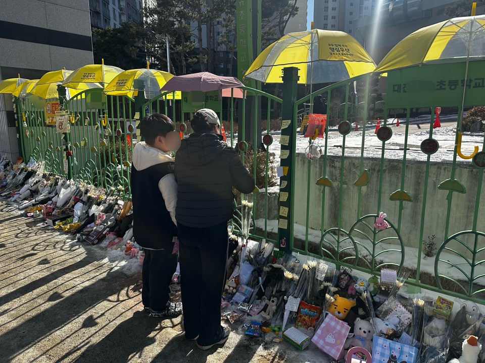 13일 고 김하늘 양이 다니던 초등학교에서 한 모자가 김 양을 추모하고 있다. 사진=서유빈 기자