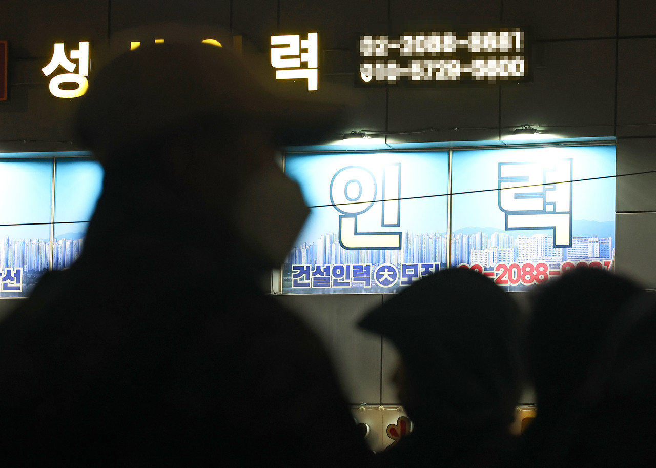 일용직 구직자들 뒤로 인력사무소의 불이 켜져 있다. 사진=연합뉴스.