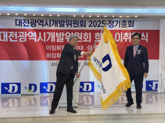 27일 계룡스파텔에서 진행된 대전시개발위원회 회장 이취임식 행사에서 이건선 신임회장이 위원회 기를 이양받아 흔들고 있다.사진=윤경식 기자.