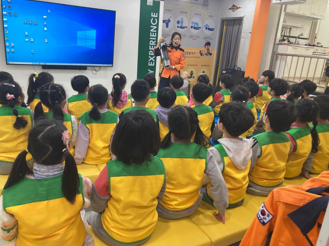 ▲한 여성 소방관이 K-소화기 사용법을 설명하자, 아이들이 진지하게 귀 기울이고 있다.