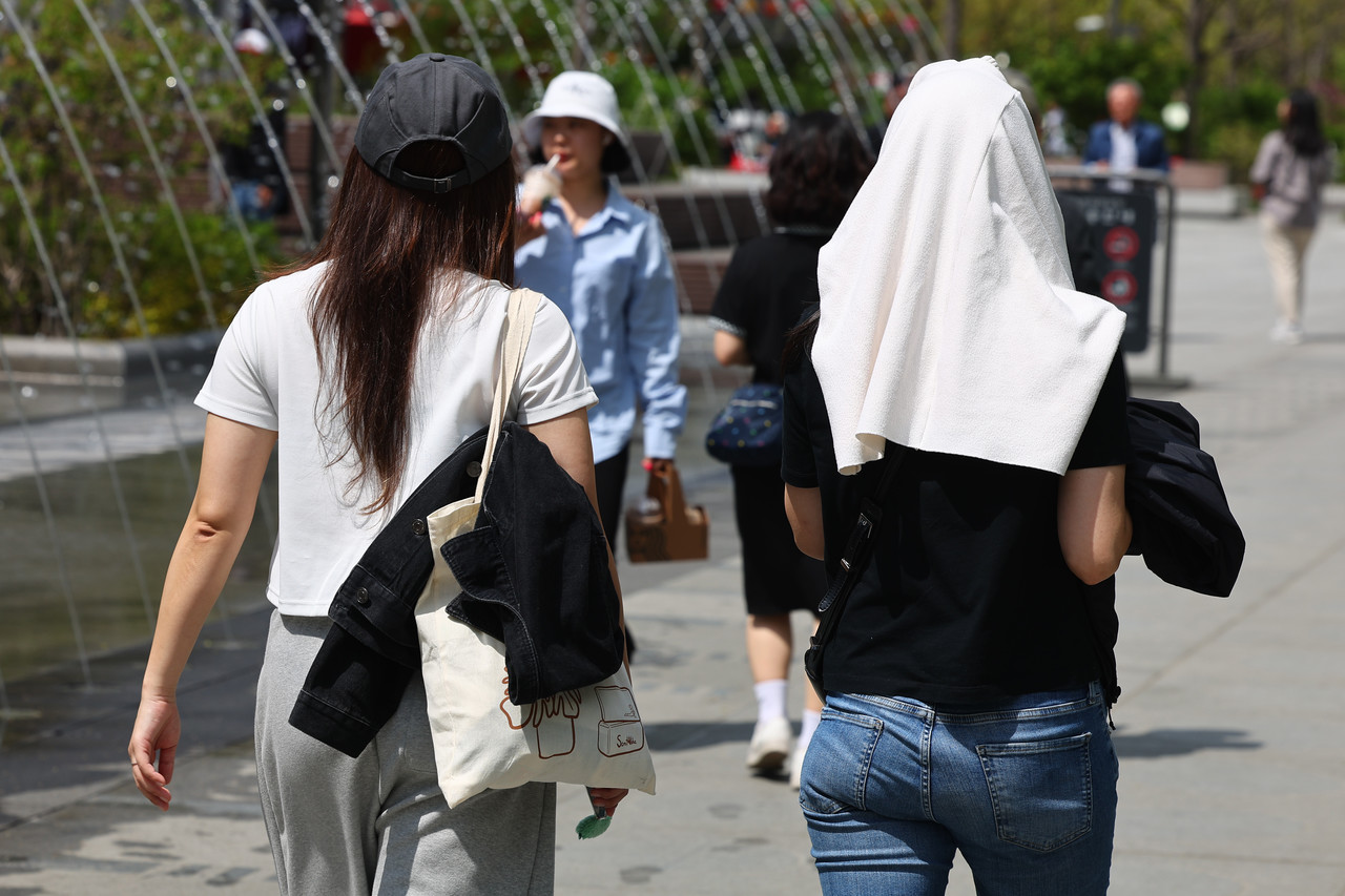서울 한낮 기온이 26도까지 치솟으며 초여름 날씨를 보인 21일 서울 종로구 광화문광장에서 시민들이 겉옷으로 햇빛을 피하며 이동하고 있다. 2025.4.21 사진=연합뉴스.