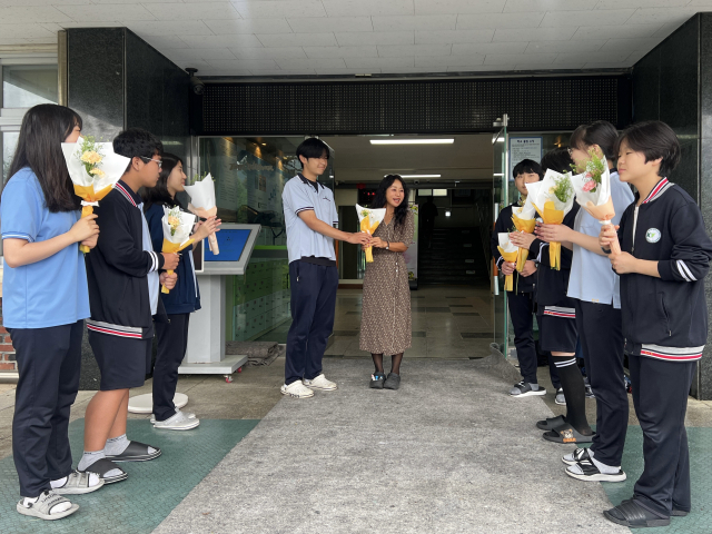 ▲스승의 날 아침, 건양중학교 학생들이 학교 현관 앞에서 여선생님께 꽃다발을 전하며 진심 어린 감사와 존경의 마음을 전하고 있다.