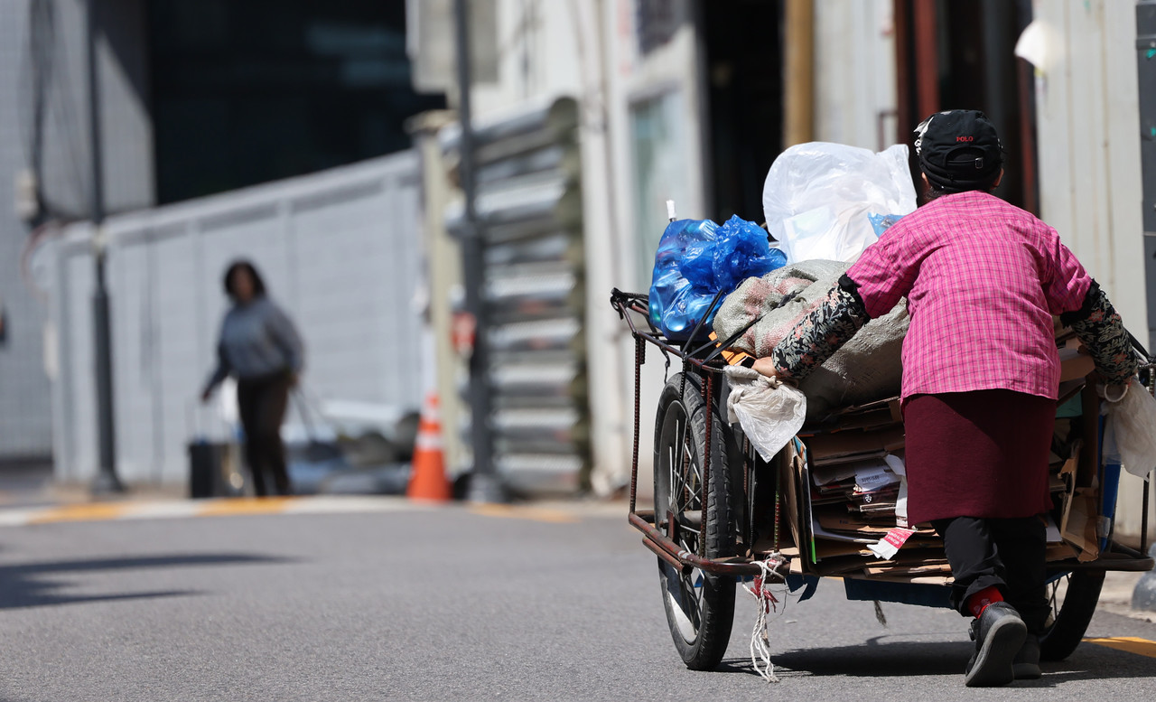 한 어르신이 폐지를 모은 손수레를 끌고 있다. 사진=연합뉴스. 