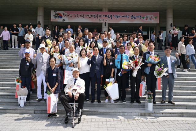 ▲회의를 마친 뒤 논산아트센터 현관 앞에서 백성현 시장과 수상자들이 함께 기념사진을 촬영하고 있다.