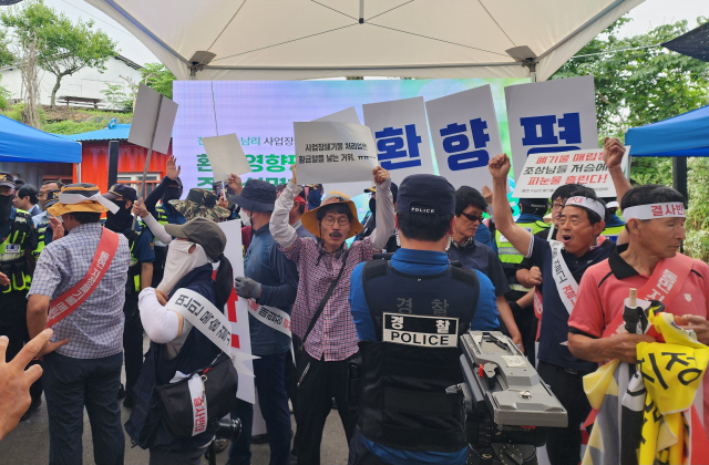 천안시 동면 폐기물매립장 조성에 관한 주민설명회가 14일 오전 수남1리 마을회관 앞에서 열린 가운데 반대 측 주민들과 환경단체 회원들이 사업 관련 영상을 가리고 “매립장 조성 반대”를 외치고 있다. 사진=박동혁 기자.