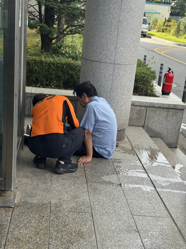 소방서 직원이 인화성 물질을 몸에 붓고 충주시청 1층 후문 바닥에 쓰러진 A씨를 부축하고 있는 모습이다.사진=김의상 기자
