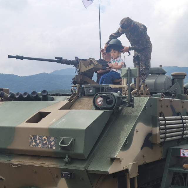 ▲계룡군문화축제 현장에서 아빠와 아이가 육군 k808차륜형 장갑차에 올라 즐겁게 포즈를 취하며 기념사진을 찍고 있는 모습. 미래의 장병을 꿈꾸는 듯한 아이의 환한 표정과 함께 가족이 함께하는 군문화 체험의 즐거움이 잘 담겼다. 사진=김흥준 기자