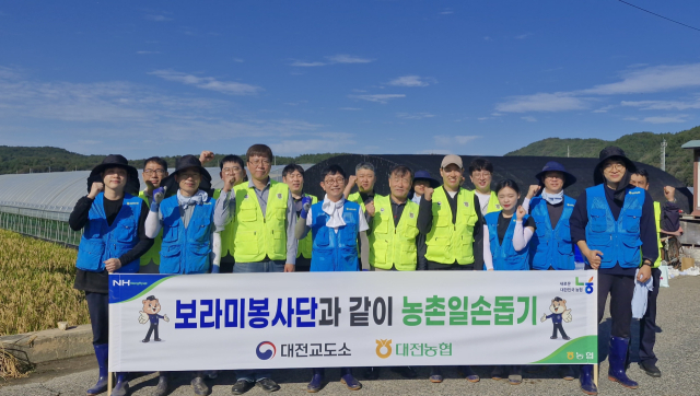 농협중앙회 대전지역본부 임직원과 대전교도소 보라미봉사단이 17일 대전지역 농가에서 일손돕기를 진행한 뒤 기념촬영을 하고 있다. 대전농협 제공