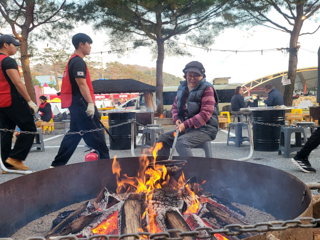 괴산김장축제 방문객이 따뜻한 모닥불에 밤을 구우며 잔잔한 미소를 띄우고 있다. 김영 기자