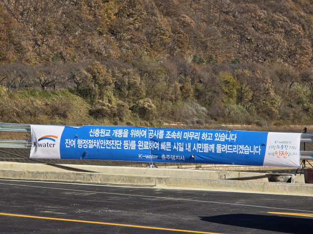 한국수자원공사 충주댐지사가 신충원교 개통을 위해 남은 안전진단 등 행정 절차를 완료한 뒤 빠른 시일 내 개통하겠다는 내용을 담은 현수막을 게시한 모습.사진=김의상 기자