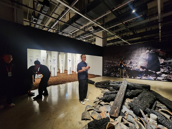 2025 청주공예비엔날레 개막 하루 전인 지난 9월 3일 사전 프레스투어가 진행되고 있다. 오준식 홍림회대표가 올해 발생한 경북 의성 산불로 전소된 고은사 잔해 앞에서 산불피해목으로 만든 지팡이에 대해 설명하고 있다. 사진=송휘헌 기자